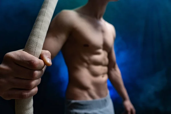 Muscular male circus artist with Cord Lisse on black an smoked background — Stock Photo, Image