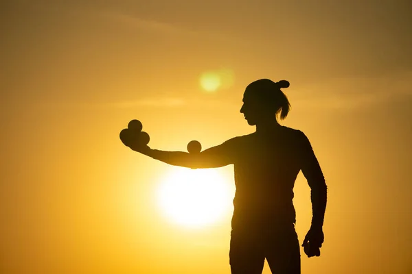 Silhouette of juggler with balls on colorful sunset — Stock Photo, Image