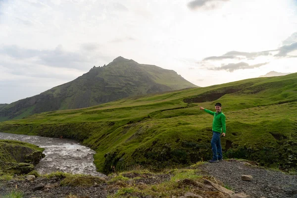 İzlanda 'da Fimmvorduhals yürüyüş yolunda arka planda nehir ve yeşil dağları olan genç bir yürüyüşçü. Özgürlük hareketi ve özgürlük kavramı — Stok fotoğraf