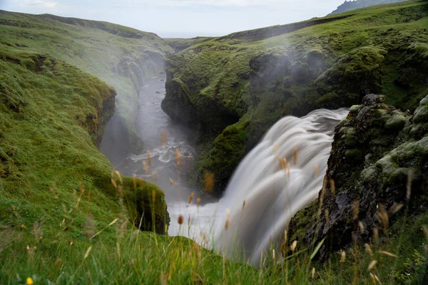 Krásný hladký vodopád na Islandu obklopen zelenými kopci — Stock fotografie