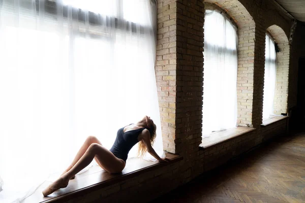 Bela bailarina no fato de banho preto posando na grande janela no salão de luz. Conceito de estilo de vida saudável — Fotografia de Stock
