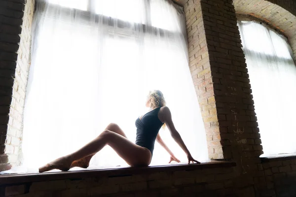 Bela bailarina no fato de banho preto posando na grande janela no salão de luz. Conceito de estilo de vida saudável — Fotografia de Stock