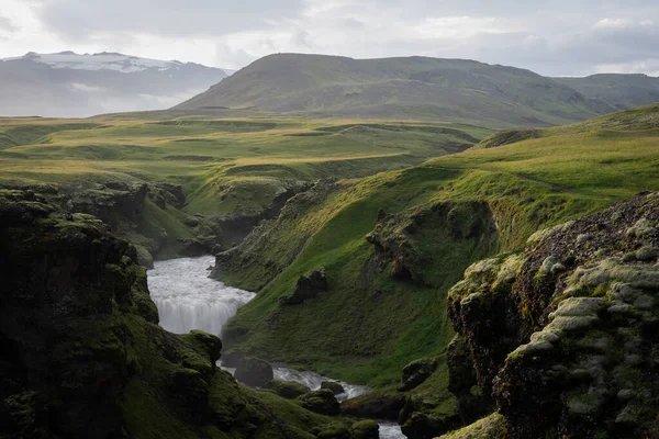 Beautiful smooth river in Iceland surrounded by green hills during the sunset on the Fimmvorduhals hiking trail close to Skogar Stock Image