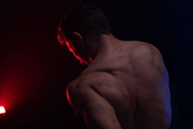 Siyah arka planda renkli dumanla izole edilmiş kasları gösteren kaslı bir adam. Sağlıklı yaşam tarzı kavramı 