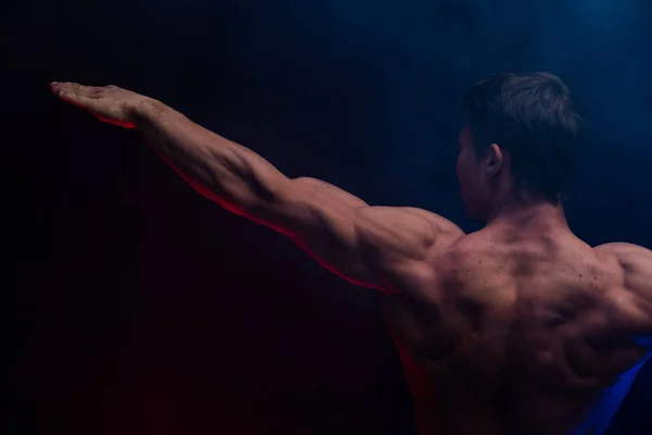 Uomo muscolare che mostra i muscoli isolati sullo sfondo nero da vicino. Concetto di stile di vita sano — Foto Stock