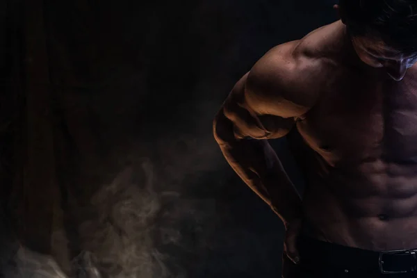 Hombre musculoso mostrando músculos aislados en el fondo negro. Concepto de estilo de vida saludable — Foto de Stock