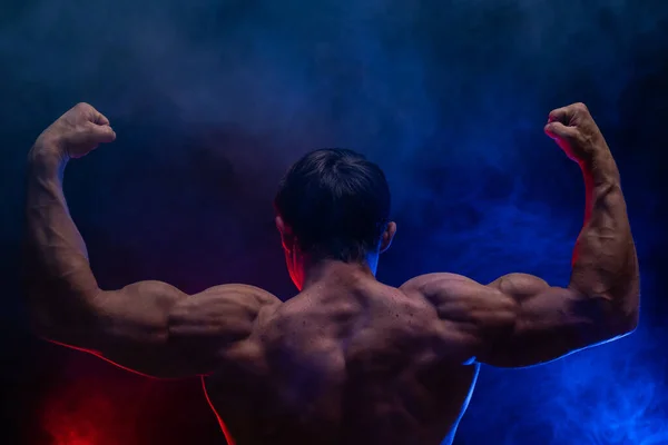黒色の背景に煙で隔離された筋肉を示す筋肉の男。健康的なライフスタイルの概念 — ストック写真