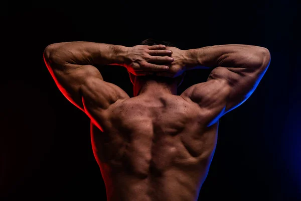 Muskulöser Mann, der auf dem schwarzen Hintergrund mit farbigem Rauch isolierte Muskeln zeigt. Konzept eines gesunden Lebensstils — Stockfoto