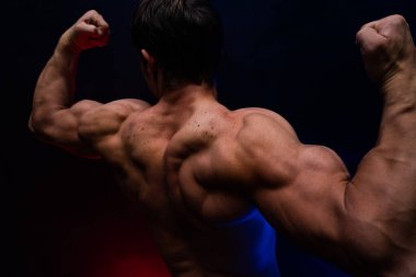 Siyah arka planda renkli dumanla izole edilmiş kasları gösteren kaslı bir adam. Sağlıklı yaşam tarzı kavramı 