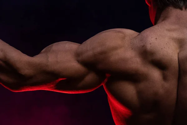 Hombre musculoso mostrando músculos aislados en el fondo negro de cerca. Concepto de estilo de vida saludable — Foto de Stock
