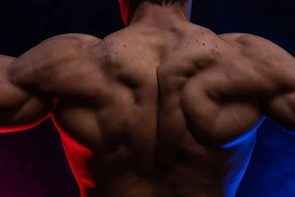 Hombre musculoso mostrando músculos aislados en el fondo negro de cerca. Concepto de estilo de vida saludable — Foto de Stock