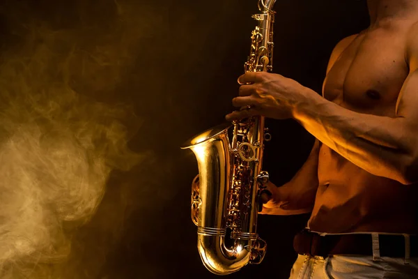 Hombre musculoso con torso desnudo tocando en saxofón con fondo colorido ahumado — Foto de Stock