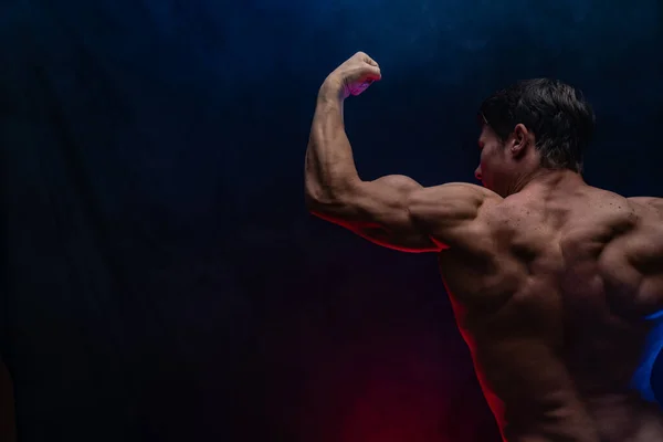 Homem musculoso mostrando músculos isolados no fundo preto. Conceito de estilo de vida saudável — Fotografia de Stock