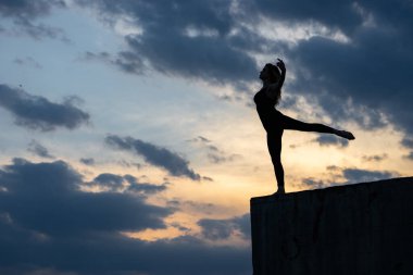 Açık hava gündoğumu arka planında genç bir bayan dansçı. Özgürlük kavramı, cesur ve mutlu bir yaşam tarzı.