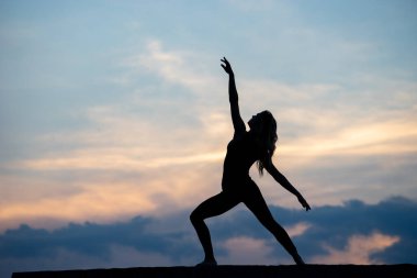 Açık hava gündoğumu arka planında iyi görünümlü bir kadın dansçı. Özgürlük kavramı ve mutlu yaşam tarzı