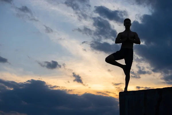 Fit jeune homme pratique le yoga de salutation au soleil sur le bord de la falaise au coucher du soleil — Photo