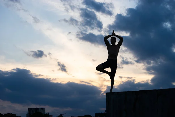 Ajuste joven practica yoga de la salutación del sol en el borde del acantilado al atardecer — Foto de Stock