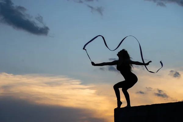 Szakmai torna nő táncos szalaggal az égen háttér — Stock Fotó