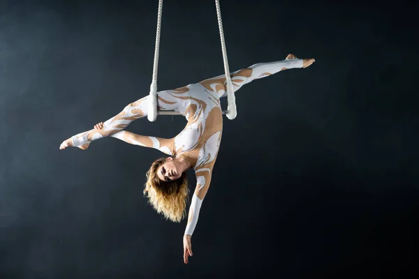 Una giovane ragazza esegue gli elementi acrobatici nel trapezio dell'aria. Studio prestazioni di ripresa su uno sfondo nero — Foto Stock