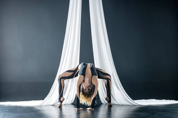 Hermosa gimnasta mujer flexible con sedas aéreas blancas aisladas sobre fondo negro — Foto de Stock