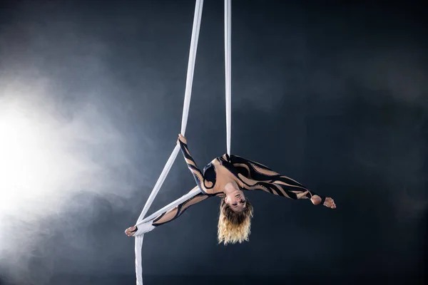 En ung flicka utför de akrobatiska elementen i det luftburna sidenet. Studio skytte föreställningar på en svart bakgrund — Stockfoto