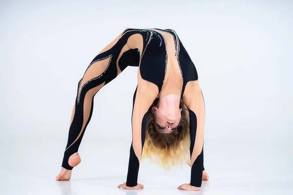 O tânără fată flexibilă efectuează elementele acrobatice de pe podea. Studio de fotografiere spectacole pe un fundal alb — Fotografie, imagine de stoc