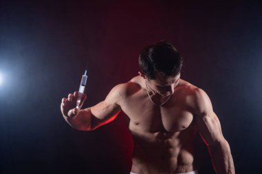 Vücut geliştirici elinde enjeksiyonla büyük bir şırınga tutuyor. Spor ve bağımlılıkta steroid kavramı 