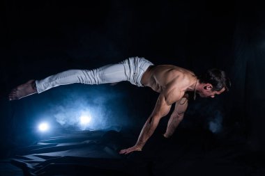 Siyah arka planda planche yapan kaslı adam.