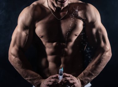 Vücut geliştirici elinde enjeksiyonla büyük bir şırınga tutuyor. Spor ve bağımlılıkta steroid kavramı 