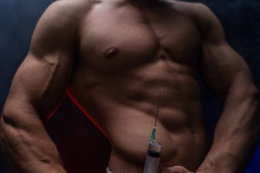 Vücut geliştirici elinde enjeksiyonla büyük bir şırınga tutuyor. Spor ve bağımlılıkta steroid kavramı 