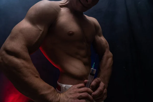 Бодибилдер держит большой шприц с инъекцией. концепция стероидов в спорте и наркомании — стоковое фото