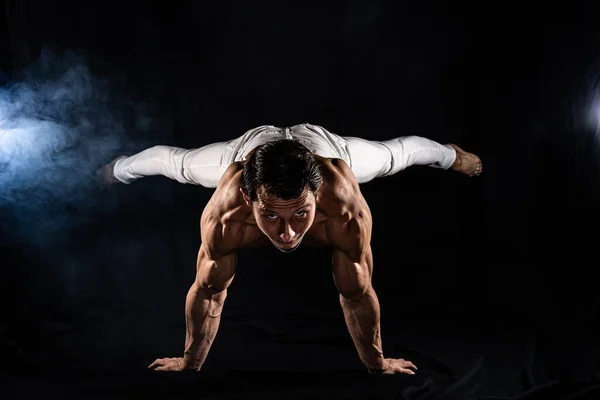 Hombre musculoso haciendo planche sobre fondo negro — Foto de Stock