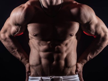 Siyah arka planda izole olmuş kasları gösteren kaslı bir adam. Vücut geliştirme ve spor salonunda vücut geliştirme kavramı 