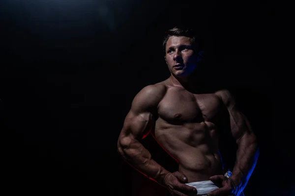 Homem musculoso mostrando músculos isolados no fundo preto. Conceito de estilo de vida saudável e cuidados de saúde — Fotografia de Stock