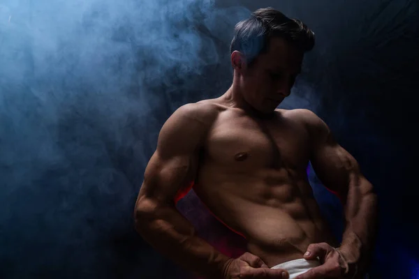 Homem musculoso mostrando músculos isolados no fundo preto. Conceito de musculação e criação de seu corpo no ginásio — Fotografia de Stock