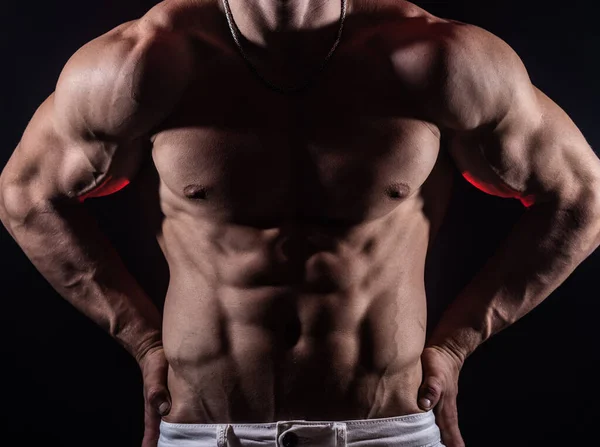 М'язова людина показує м'язи ізольовані на чорному тлі. Концепція бодібілдингу і створення вашого тіла в спортзалі — стокове фото