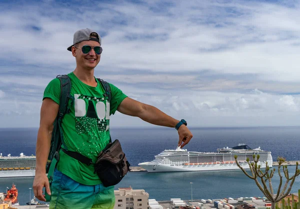 Concepto de vacaciones en crucero. Joven hombre guapo sosteniendo en la mano atracado crucero en el puerto — Foto de Stock