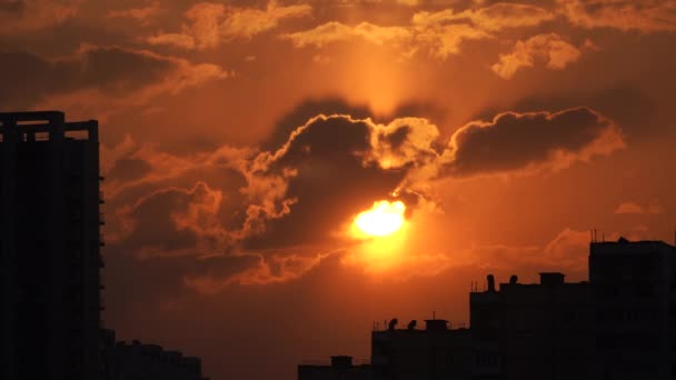 劇的な夕日オレンジの雲と太陽のディスクと都市のシルエット — ストック動画