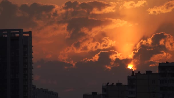 Міський силует з драматичним заходом сонця помаранчеві хмари і сонячний диск — стокове відео