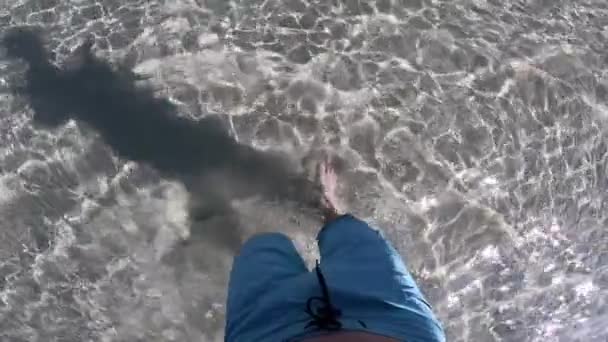 Close-up na perna do jovem andando por água cristalina na costa do mar em câmera lenta — Vídeo de Stock