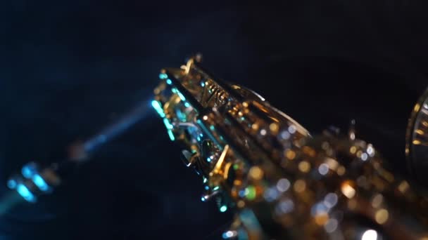 Saxofón alto dorado brillante sobre fondo negro con humo azul — Vídeo de stock