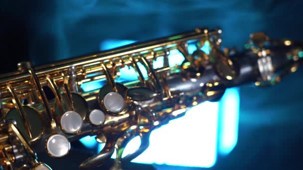 Goldenes glänzendes Altsaxophon auf schwarzem Hintergrund mit blauem Rauch — Stockvideo