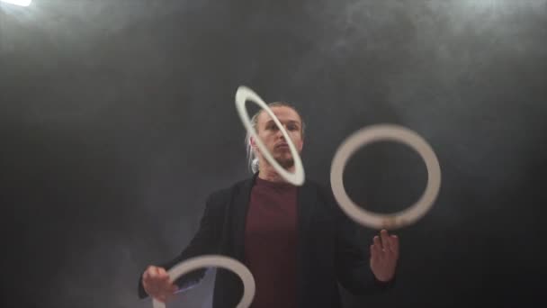 Мужчина в черном жонглирует белыми кольцами. Управление, контроль и успех — стоковое видео