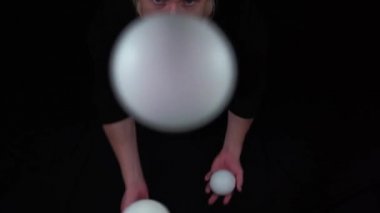 Sirk sanatçısı beyaz toplarla siyah jonglörlük yapıyor..