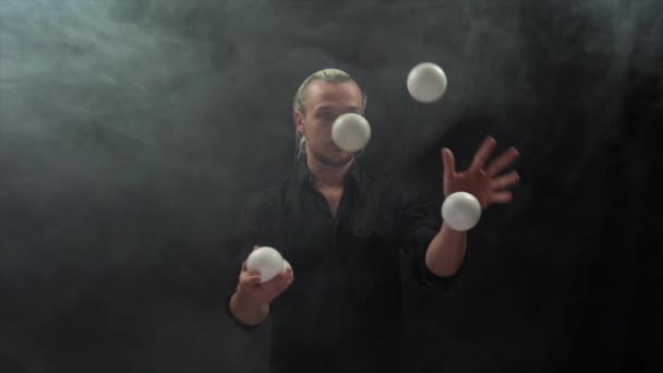 Een man met een zwart jongleren met witte ballen. Beheer, controle en succes — Stockvideo