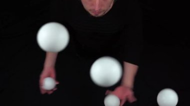 Sirk sanatçısı beyaz toplarla siyah jonglörlük yapıyor..