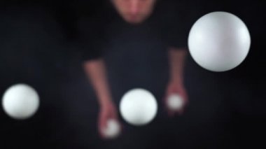 Sirk sanatçısı ağır çekimde siyah ve beyaz toplarla hokkabazlık yapıyor