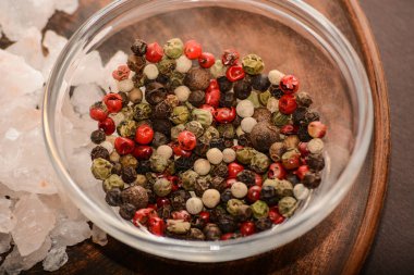 Bütün karabiber ve gül tuz kümesi. Avuç kırmızı, siyah, beyaz karabiber ve tuz argil plaka üzerinde