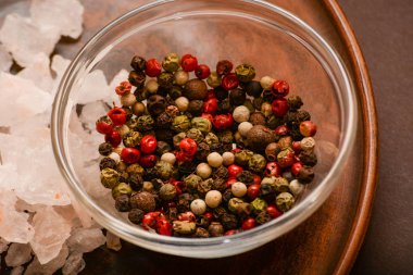 Bütün karabiber ve gül tuz kümesi. Avuç kırmızı, siyah, beyaz karabiber ve tuz argil plaka üzerinde