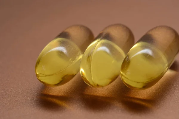 Cápsulas de óleo de peixe com ómega 3 e vitamina D em uma textura brilhante, conceito de dieta saudável — Fotografia de Stock